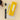 a desktop view of a yellow pen case made of plastic with write-in sticker next to a yellow ball-point pen laying on top pf a notebook that reads penco and A5